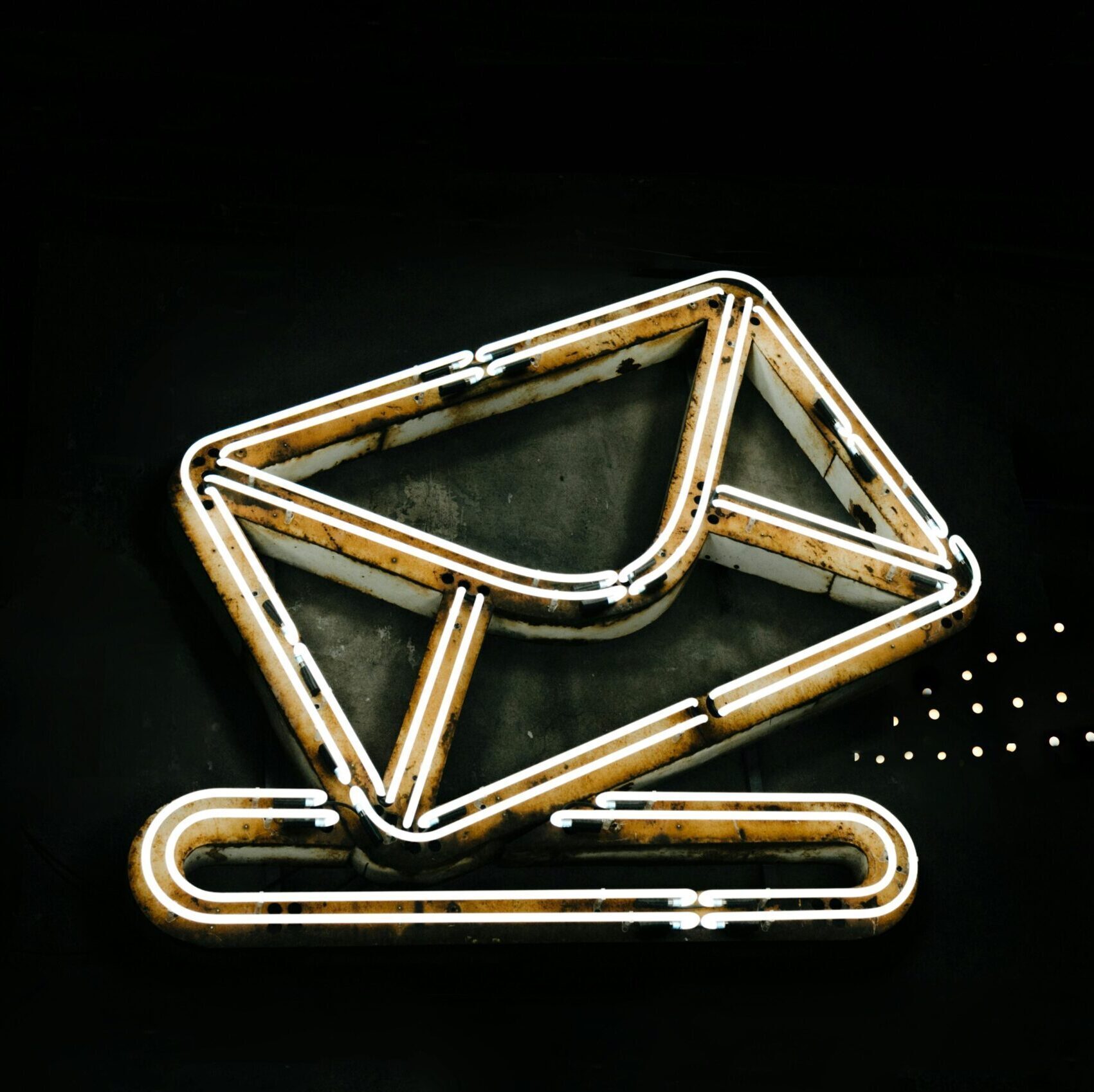 A glowing neon envelope symbol against a black background, conveying messaging or email concept.