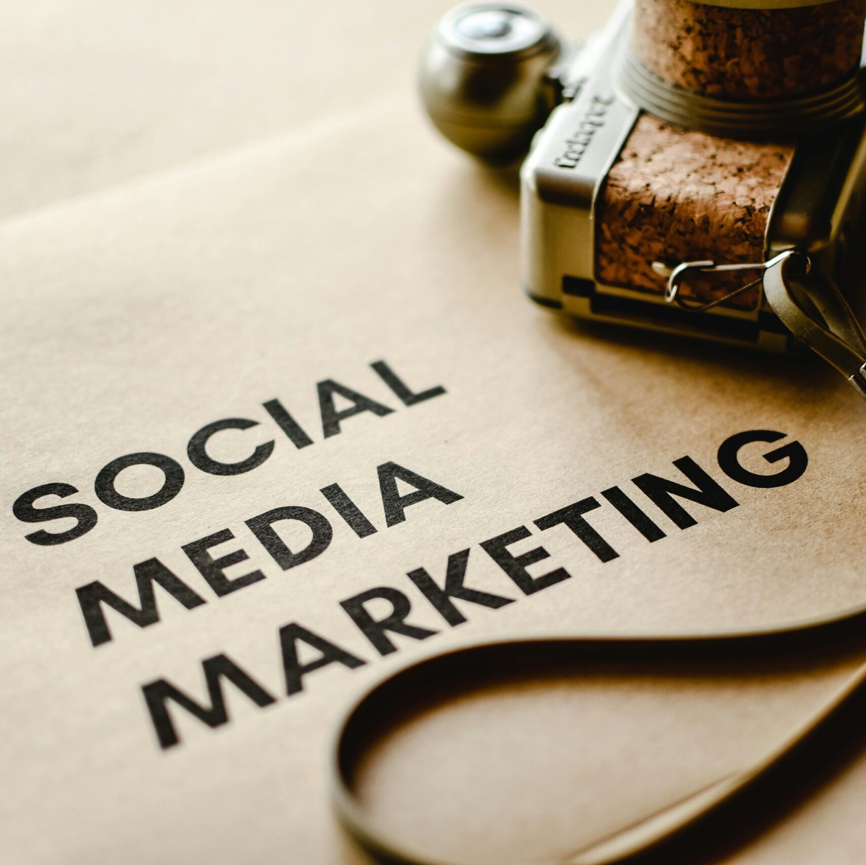 Close-up of a camera placed on brown paper with 'Social Media Marketing' text, emphasizing digital marketing themes.